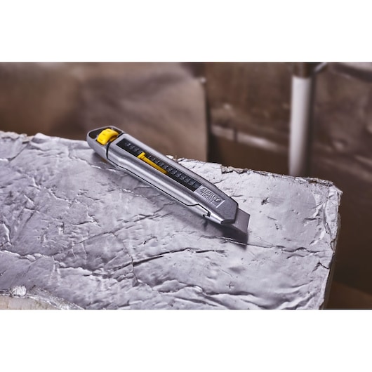 STANLEY 0-10-018 utility knife with retractable blade, silver and yellow, shown on a metallic surface.