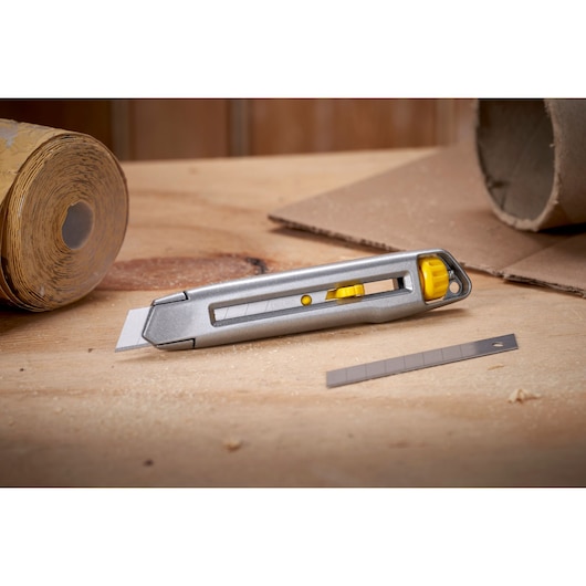 Photo of STANLEY 0-10-018 utility knife with yellow accents and extra blade on workbench, product category: Photography.