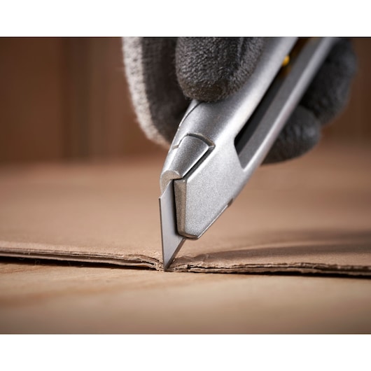 STANLEY 0-10-018 utility knife cutting cardboard, close-up, photography of hand wearing glove.