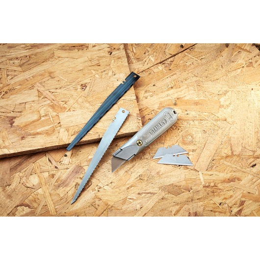 STANLEY 0-10-129 folding utility knife with blade, saw blade, cover, and spare blades on wood surface.