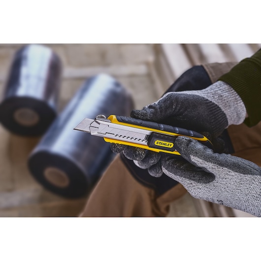 Photo of STANLEY 0-10-481 utility knife with segmented blade, held in a gloved hand, product in use.