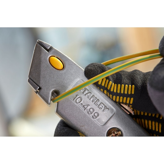 STANLEY 0-10-499 utility knife silver body with yellow button in gloved hand, close-up side angle.