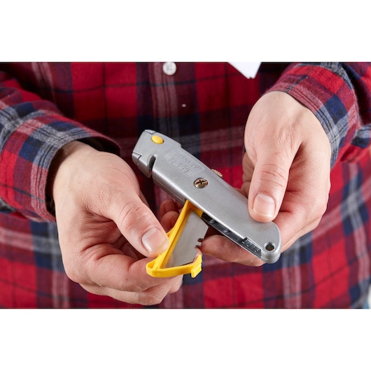 Photo of STANLEY 0-10-499 utility knife with yellow blade compartment held in hand, Product Category: Photography.