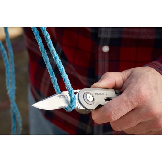 STANLEY 0-10-813 folding utility knife cutting blue rope, close-up view.