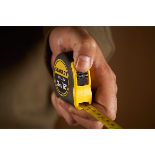 Photo of STANLEY 0-30-686 tape measure held in hand, yellow and black casing, extended measuring tape.