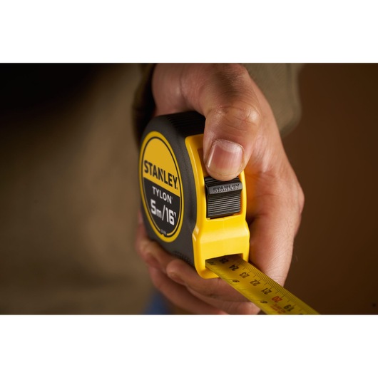 Photo of STANLEY 0-30-696 tape measure Tylon 5m/16ft held in hand, yellow and black exterior.
