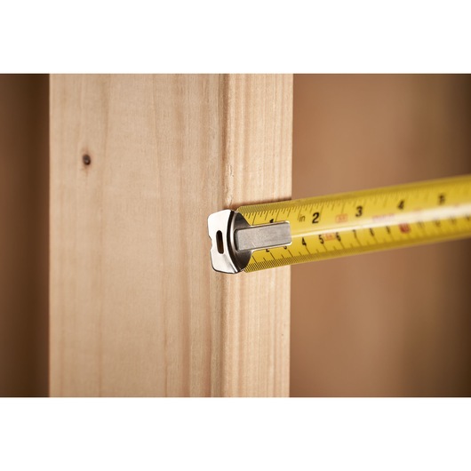 STANLEY 0-33-526 tape measure in use measuring wood, close-up side view.