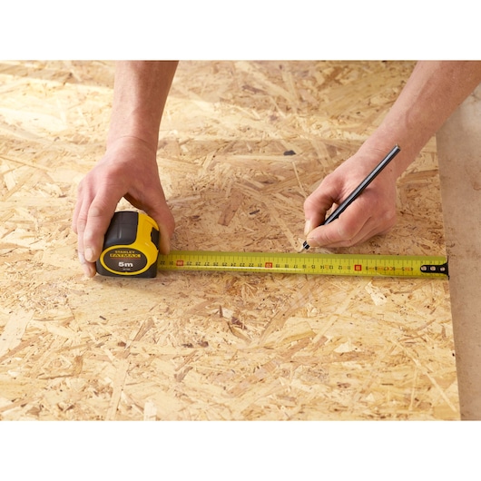 Photography of STANLEY 0-33-720 tape measure used to mark measurements on plywood surface.