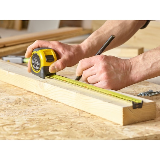STANLEY 0-33-726 tape measure used for marking wood, close-up angle, product category photography.