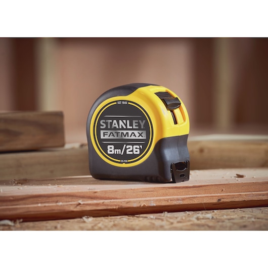 STANLEY 0-33-726 FATMAX tape measure, black and yellow, side angle, on wooden surface.