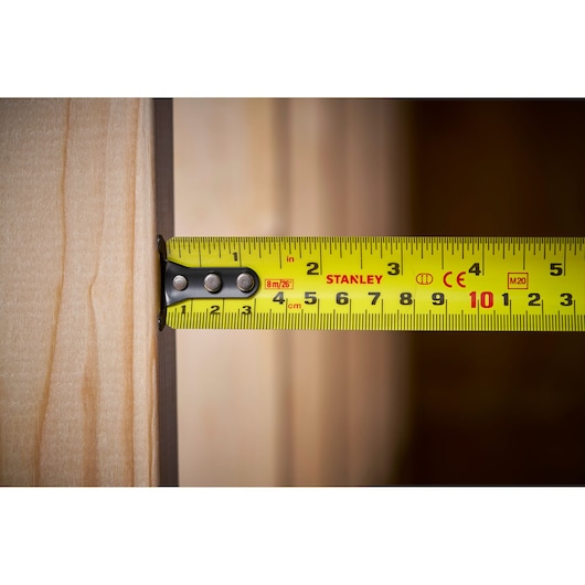 STANLEY 0-33-726 tape measure in use, measuring distance on a wooden plank, close-up view.
