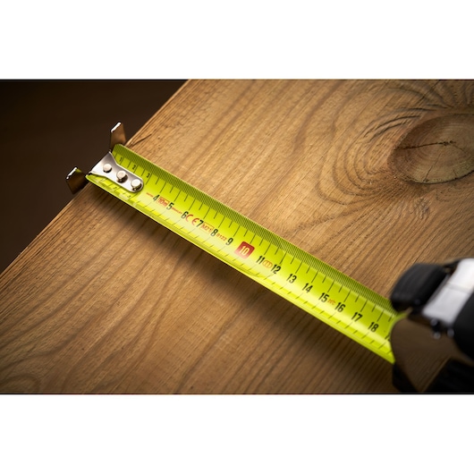 Stanley 0-33-897 tape measure on wood surface, close up showing yellow blade and measurement markings.