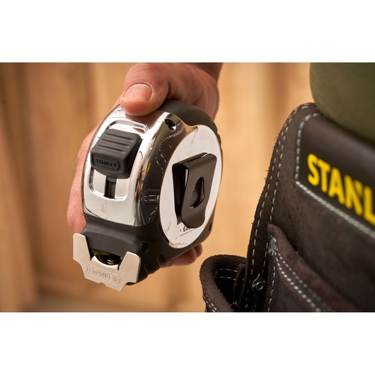 STANLEY 0-33-897 tape measure held next to tool belt, close-up photo.
