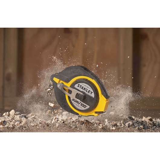 STANLEY 0-34-132 yellow tape measure photography showing measurement markings on a sandy surface.