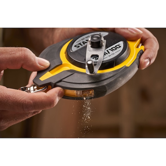 Photography of STANLEY 0-34-132 chalk line reel in use, black and yellow body, close-up view.
