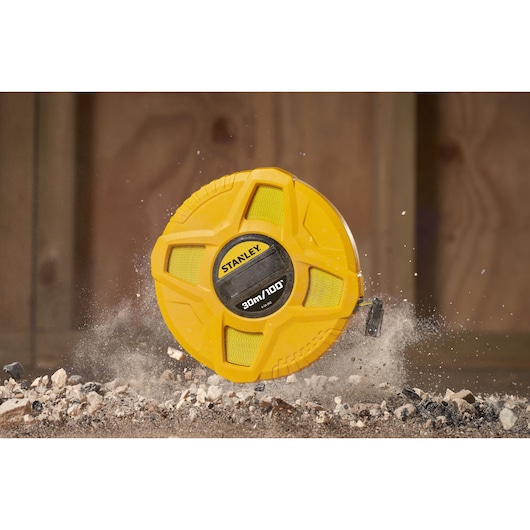 STANLEY 0-34-262 yellow tape measure, rugged design, lying on dusty ground, construction setting.