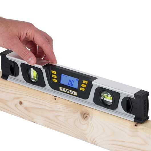 Photo of STANLEY 0-42-063 digital spirit level on wood beam, LCD screen displays 0.0, hand adjusting tool.