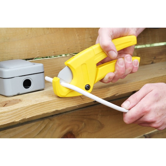 STANLEY 0-70-450 pipe cutter cutting white plastic pipe, handheld, close-up photo.