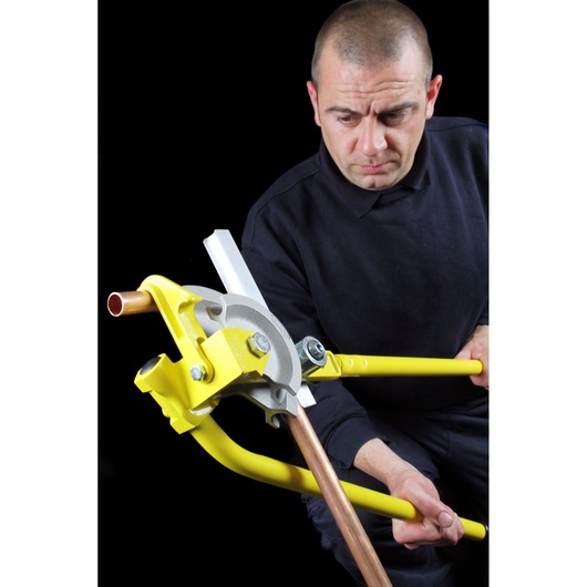 STANLEY 0-70-452 pipe bender with yellow handles in use bending a copper pipe, close-up photography.
