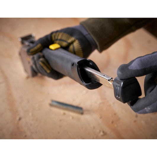 STANLEY 0-PHT350 stapler tool close-up showing reloading mechanism, with gloved hands on wood surface.