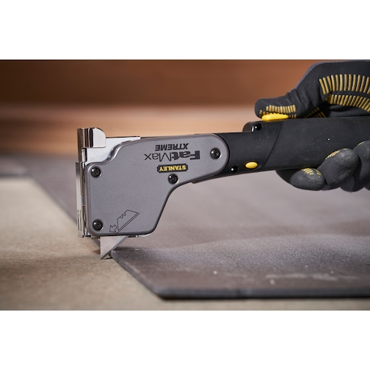 Photo of STANLEY 0-PHT350 hand staple gun with black and yellow handle in use on a flat surface.
