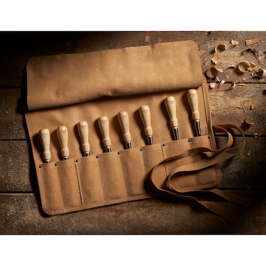 STANLEY 1-16-793 chisel set in tan suede roll, wooden handles, photographed from above on rustic table.