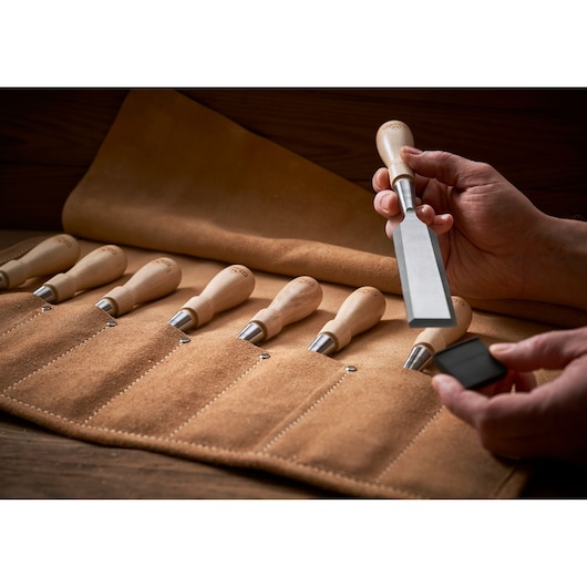 STANLEY 1-16-793 chisel set with wooden handles in tan leather roll, close-up with hand holding tool.