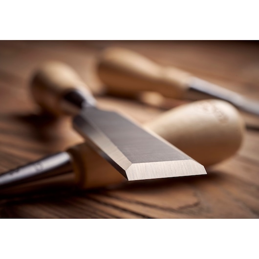 STANLEY 1-16-793 photography of wood chisel with sharp steel blade and wooden handle on wooden surface.