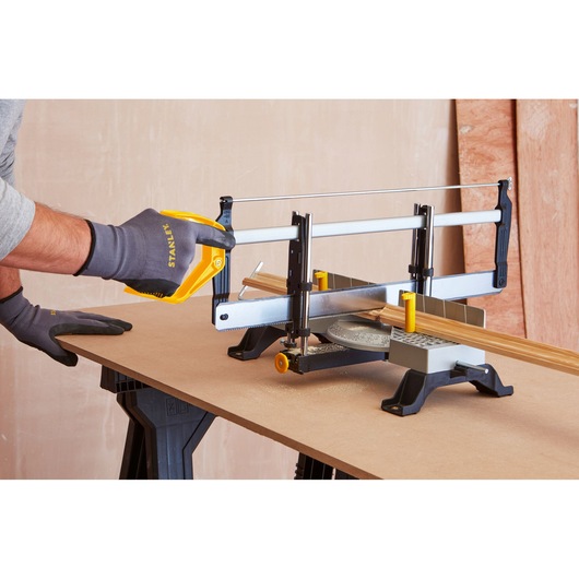 STANLEY 1-20-800 manual mitre saw on workbench cutting wood, person wearing STANLEY gloves operating saw.