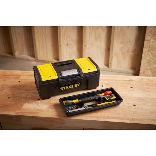 STANLEY 1-79-216 black and yellow toolbox on wooden workbench, open tray showing hand tools, workshop background.