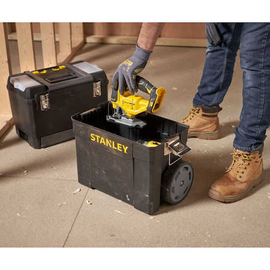 STANLEY 1-93-968 rolling toolbox in use, black with yellow logo, photographed on a workshop floor.
