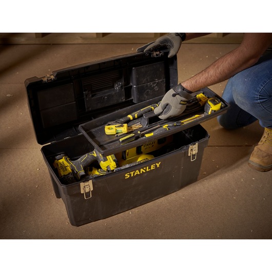 STANLEY 1-94-859 photography of black tool box with yellow tools on workshop floor, lid open, angled view.