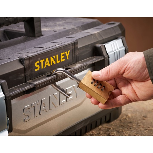 A hand unlocking a combination padlock on a Stanley toolbox.