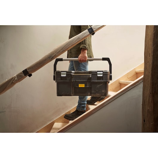 STANLEY 1-97-506 tool box being carried on stairs, black plastic case with metal handle and clasps.