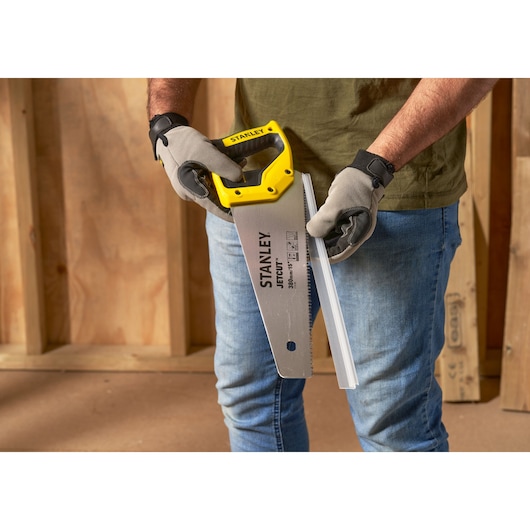 STANLEY 2-15-281 hand saw with yellow handle, photographed in use cutting a white plastic profile.
