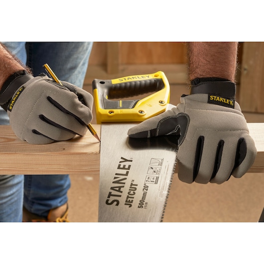 Photo of STANLEY 2-15-288 hand saw and gloves marking wood, with yellow saw handle visible in workshop.