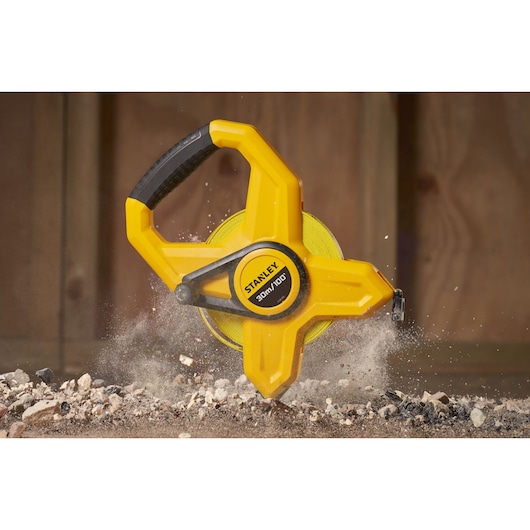 STANLEY 2-34-791 open reel measuring tape with yellow case and black handle on construction site.
