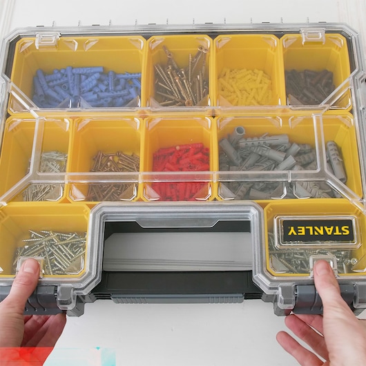 STANLEY 22910 organizer box with yellow compartments holding assorted screws and wall plugs, top view.