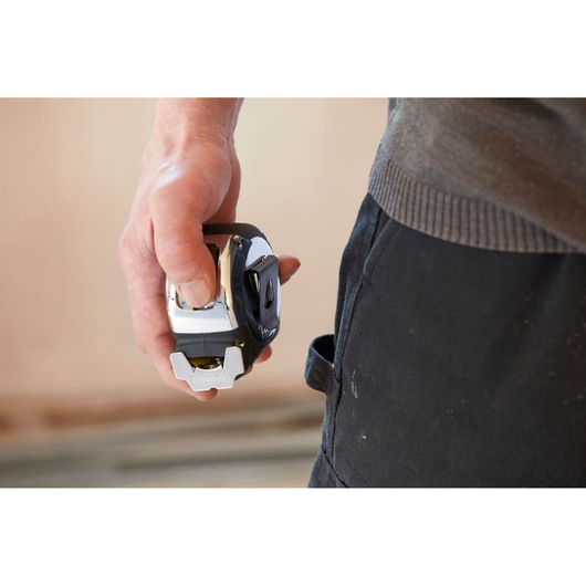STANLEY 5-33-891 tape measure held in hand near work pants, product photography.