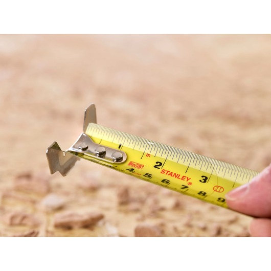 STANLEY 5-33-891 tape measure close-up showing yellow blade with clear markings in outdoor setting.