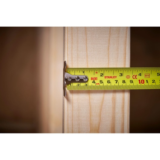 STANLEY 5-33-891 tape measure measuring wooden beam, close-up, clear metric markings.