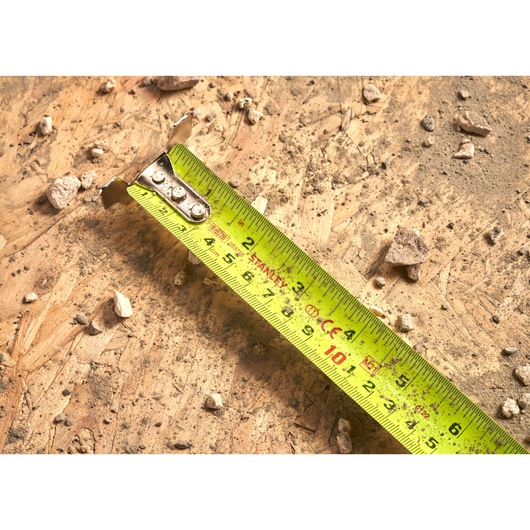 Photo of STANLEY 5-33-891 tape measure with yellow blade on a dusty wooden surface with small debris.