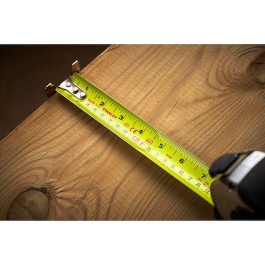 Stanley 5-33-896 tape measure photography, yellow blade measuring wood surface close-up.