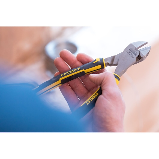 Photo of STANLEY 89-859 diagonal cutting pliers with black and yellow handles held in a hand, side view.