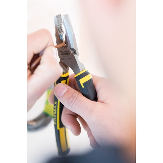 Photo of STANLEY 89-867 combination pliers with black and yellow handles gripping a brown wire in use.