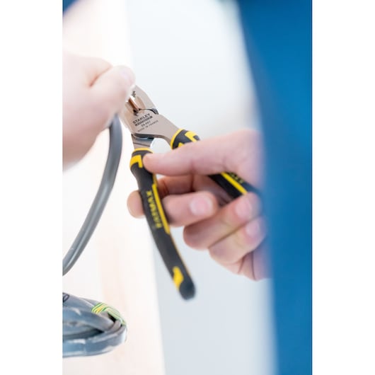 STANLEY 89-867 cutting pliers with black and yellow handle cutting a wire, close-up photography.