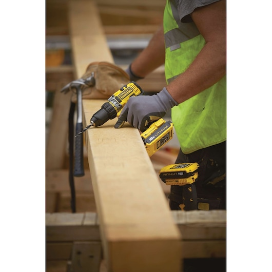 STANLEY FMC600B cordless drill in use on wood plank, yellow and black design, construction setting.