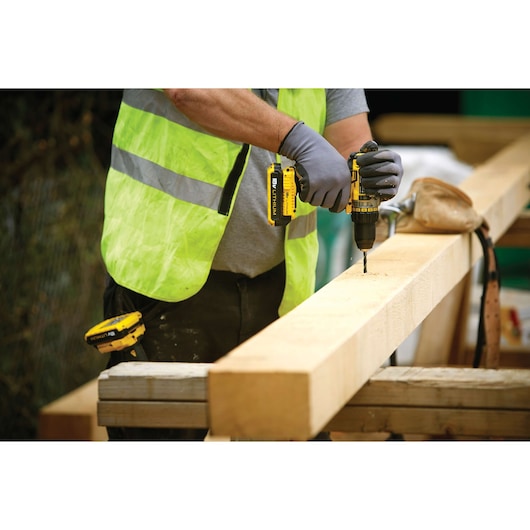 STANLEY FMC600B drill being used on wood by a person in a hi-vis vest and gloves.