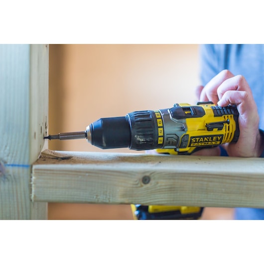 STANLEY FMC625D2 cordless drill being used to drive a screw into wood, close-up side view.