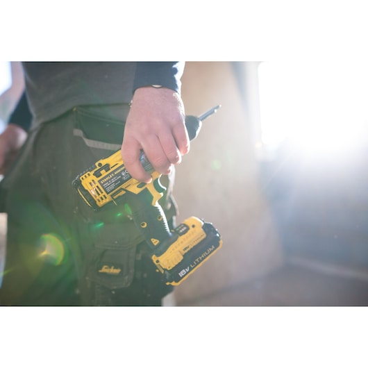 Photo of STANLEY FMC625D2 cordless drill-driver held by a person, 18V Lithium battery visible.